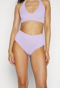 Conjunto de biquíni lilás com detalhe canelado, top de halter e parte de baixo de cintura alta, apresentando um acabamento texturizado e um acabamento contrastante.