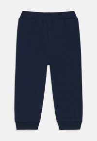 Calças de fato azul-marinho feitas de um tecido macio, apresentando um cós canelado, punhos elásticos e uma textura suave; sem padrões ou acessórios adicionais.