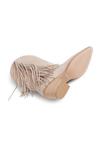 Botín de tobillo beige con flecos, con una parte superior de ante texturizado, un tacón de madera apilada y una suela de goma con estrías horizontales.