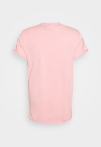 T-shirt en coton rose à manches courtes, col rond et coupe décontractée. Texture lisse et sans motifs ni graphismes visibles.