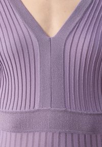Haut tricoté violet avec un design en V, des côtes verticales, une texture lisse et une taille ajustée. Détails scintillants remarquables.