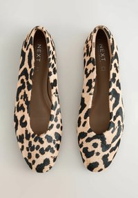 Beige en zwarte ballerina's met luipaardprint, gemaakt van dierenhaar met een gladde textuur. Rond neuzen en uitgesneden zijkanten.