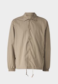 Jasnobeżowa kurtka wykonana z teksturowanej tkaniny. Posiada kołnierz, zapięcia na zatrzaski, elastyczne mankiety oraz regulowany sznurek w dolnym obszyciu.