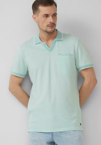 Muntgroene polo shirt van een gestructureerde stof, met een V-hals, korte mouwen met contrasterende afwerking en een klein borstzakje.