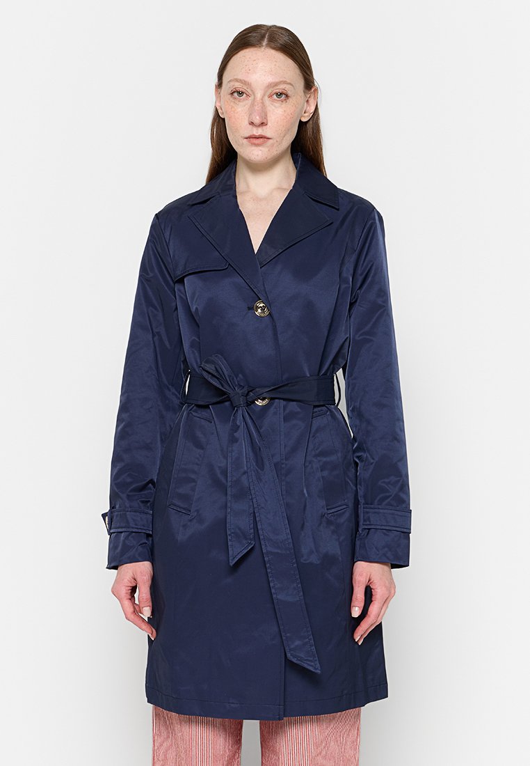Cappotto trench blu navy realizzato in tessuto liscio, con vita sfiancata da una cintura, colletto ampio, due tasche frontali e chiusura con un solo bottone.