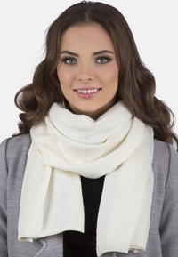 Bílý pletený šál s hladkou texturou, volně omotaný kolem krku, s jednoduchým designem a rovnou hranou.