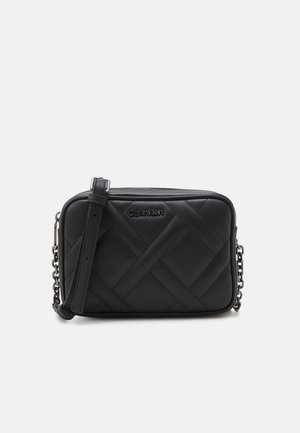 Sac bandoulière en cuir matelassé noir avec bandoulière réglable, détail chaîne et logo discret Calvin Klein sur le devant.