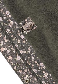 Fliso antklodė su alyvuogių žalios spalvos viena puse ir gėlių raštu su pastelinių spalvų gėlėmis, papildyta užtrauktuku ir užsegimu su sagtele.