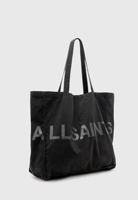 Zwarte canvas tote bag met twee schouderbanden en grote "ALLSAINTS" lettering in grijs. Zachte textuur, rechthoekige vorm, minimalistisch ontwerp.
