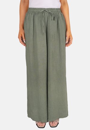Pantalon large en lin couleur vert olive avec taille élastique et cordon de serrage, porté avec un haut blanc et des sandales noires à brides.