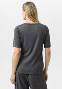 Grijze T-shirt met korte mouwen en een ronde hals. Zacht, gestructureerd materiaal met een subtiele glans, dat aan de achterkant uitloopt in een relaxte pasvorm.