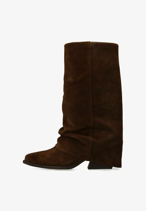 Brown suede knee-high boot with a slouch design, pointed toe, and a low block heel. Features smooth texture and minimal stitching accents.