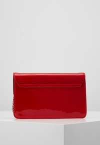 Rød patentlæder clutchtaske med rektangulær form, klaplukning og kæderem. Glat overflade med kontrastsyede detaljer.