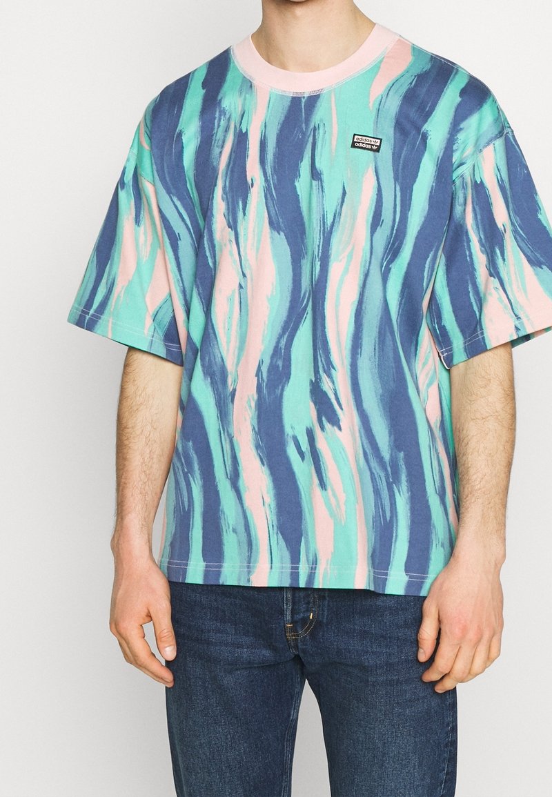 Tričko s krátkým rukávem v barvách smaragdové, modré a růžové s vířivým vzorem a černou nášivkou loga. Vyrobeno z bavlny; volný střih, kulatý výstřih.