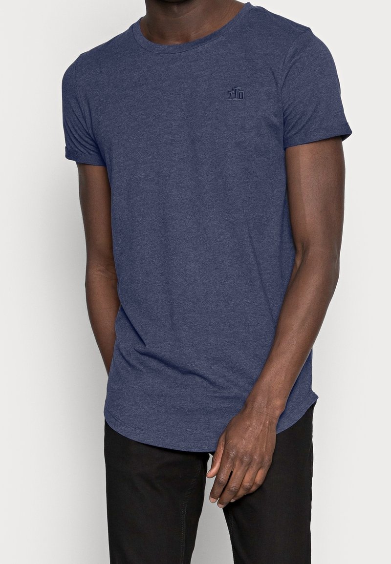 Mörkblå t-shirt med kort ärm gjord av mjukt, texturerat material med rund halsringning och en liten logotypdetalj på bröstet.