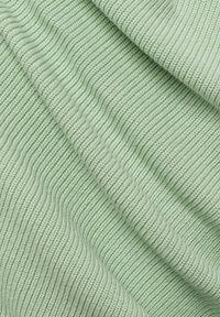 Ljust grönt ribbat tyg med en mjuk textur, med parallella fåror och en subtil lyster, idealiskt för kläder eller mjuka möbler.