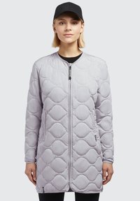 Manteau long matelassé gris clair avec un col rond, fermeture éclair à l'avant et poignets extensibles ; associé à une casquette noire. Texture lisse, sans motifs.