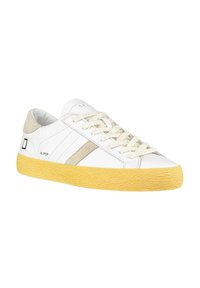 Sneakers bianchi con suola in gomma gialla, dettagli beige, parte superiore testurizzata e lacci intrecciati. Presentano il logo del marchio sul lato e un design con punta rotonda.