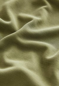 Maslinasto zeleni materijal s mekanom, glatkom teksturom, koji ima suptilne nabore i lagani, rastezljivi materijal.