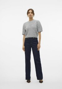 Hellgrauer, strukturierter Pullover mit kurzen Ärmeln, kombiniert mit dunkelblauen, hoch taillierten Jeans mit geradem Bein und dunkler Naht.