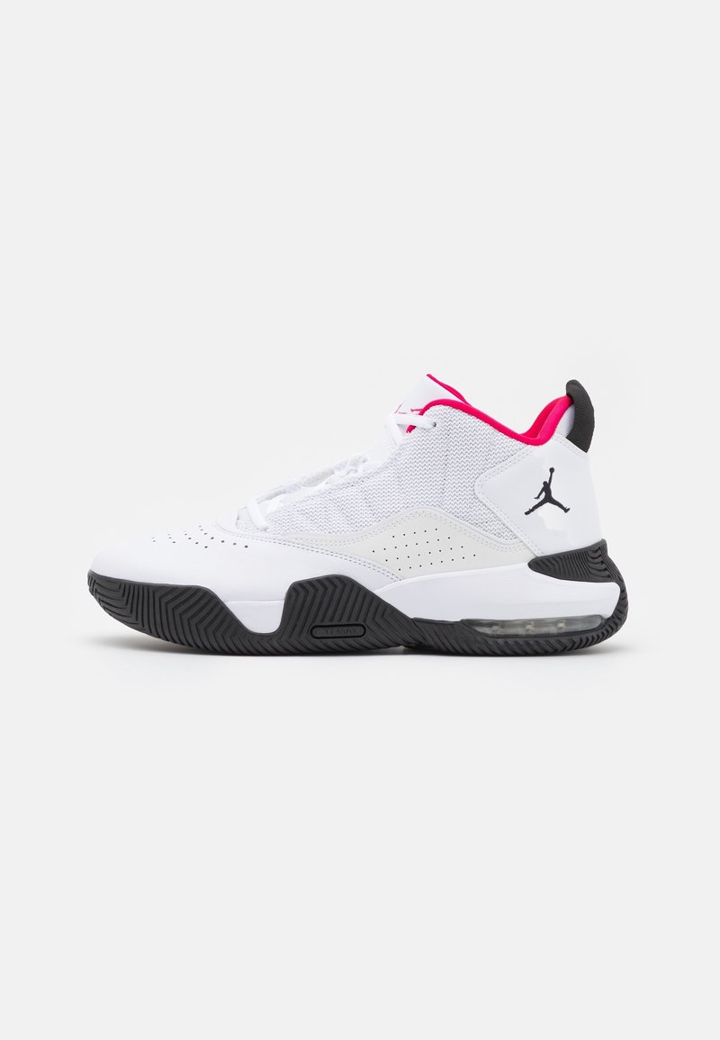 Baskets montantes blanches et noires avec une doublure intérieure rouge et un logo Jumpman noir sur le talon, vues de côté.