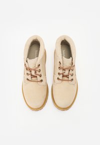 Beige suède enkellaarsjes met bruine veters, een gewatteerde kraag en een gestructureerde rubberen zool, met ventilatiegaten en verstevigde stiksels.