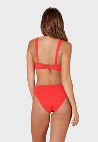 Red bikini set featuring a cropped top with wide straps and a tie-back, paired with low-rise bottoms, all in smooth, stretchy fabric.