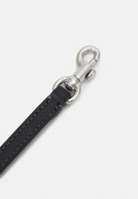 Musta nahkavyö harmaan ompeleen kanssa, varustettuna hopeisella metallisulkimella ja kiinnitysrengalla. Sujuva pinta, minimalistinen muotoilu.