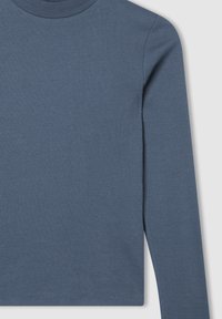 Długi rękaw w prążkowanej tkaninie, z wysokim dekoltem. Kolor: stonowany niebieski. Bezszwowe boki i dopasowana sylwetka.