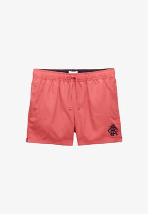 Koralowe różowe szorty kąpielowe z elastycznym paskiem w talii, z przodu związywane sznurkiem, bocznymi kieszeniami, małymi rozcięciami po bokach i granatowym logo na lewej nogawce.