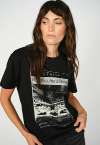Zwarte katoenen t-shirt met een grafische print van de Ponte Vecchio in Florence, met witte tekst en een contrasterend artistiek ontwerp.