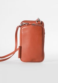 Rechthoekige, met rits afgesloten tas van bruin leer met een gladde textuur. Bevat een afneembare schouderband en een zijtab voor extra grip.