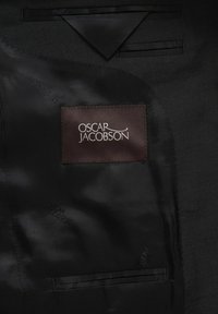 Binnenkant van een zwart colbert met een satijnachtige textuur. Bevat een bruine label met "OSCAR JACOBSON" geborduurd in het wit.