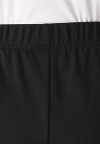 Juodas tamprus audinys su elastingu liemenu ir lygiu paviršiumi, turi siuvimo detales. Sukurtas patogumui ir lankstumui.