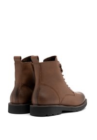 Brązowe skórzane botki sięgające kostki z teksturowanym wykończeniem, sznurowanym stylem, wyściółką na kołnierzu oraz czarną gumową podeszwą z bieżnikiem.