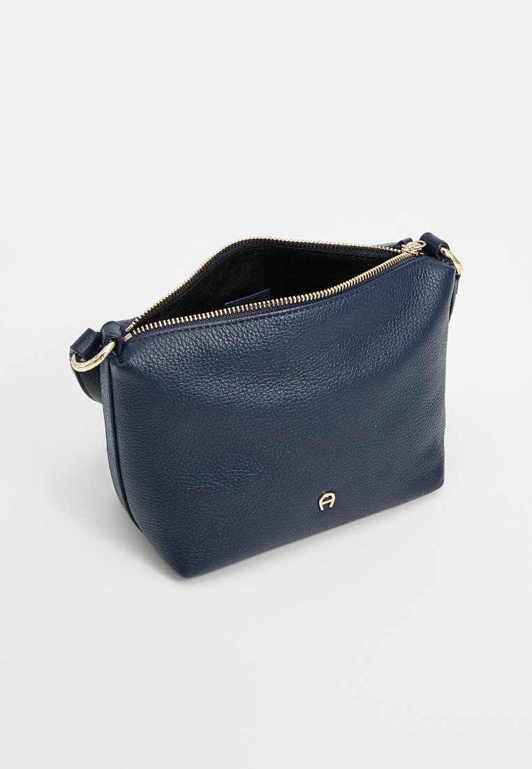 Marineblaue Leder-Crossbody-Tasche mit strukturiertem Finish, einem goldenen Reißverschluss und einem Logo-Akzent auf der Vorderseite, das ein geräumiges schwarzes Innenfach bietet.