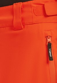 Felgekleurde oranje shorts van duurzaam materiaal met een ritszak met zwarte hardware, een brede tailleband en een lus voor aanpassing.