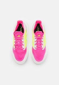 Baskets de sport roses vives avec des accents jaunes, tige en mesh texturé, semelle intermédiaire blanche et doublure intérieure noire avec le texte "PUR" et "OST".