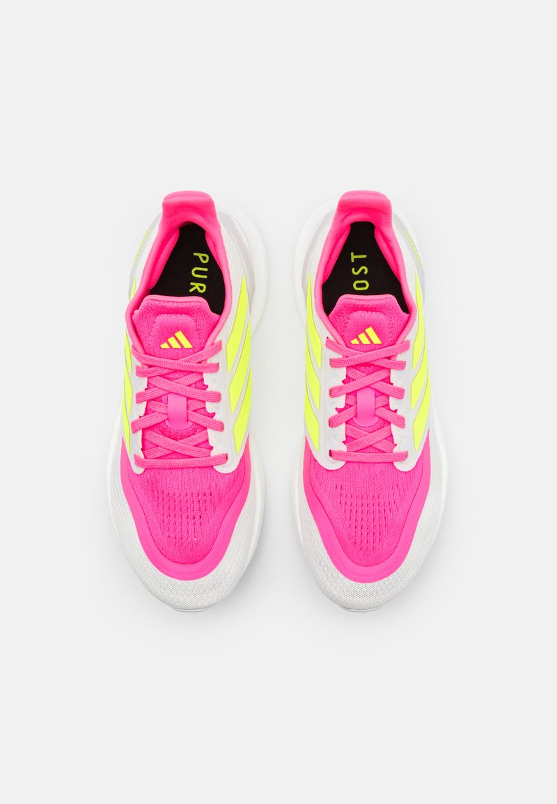 Zapatillas deportivas de color rosa brillante con detalles amarillos, parte superior de malla texturizada, entresuela blanca y forro interior negro con el texto "PUR" y "OST".