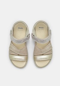 Nahka-sandaalit pehmeissä beige- ja kultasävyissä, joissa on säädettävät hihnat hienovaraisella kimalteella ja teksturoitu pohja mukavuutta varten.