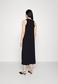 Schwarzes ärmelloses Kleid aus glattem Stoff, mit geradem Schnitt, knöchellang, mit einer schlichten Rückennaht und minimalen Designdetails.