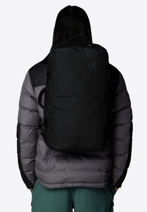 Sac à dos noir en tissu durable, au design rectangulaire, avec des bretelles ajustables et un détail de logo à l'avant.