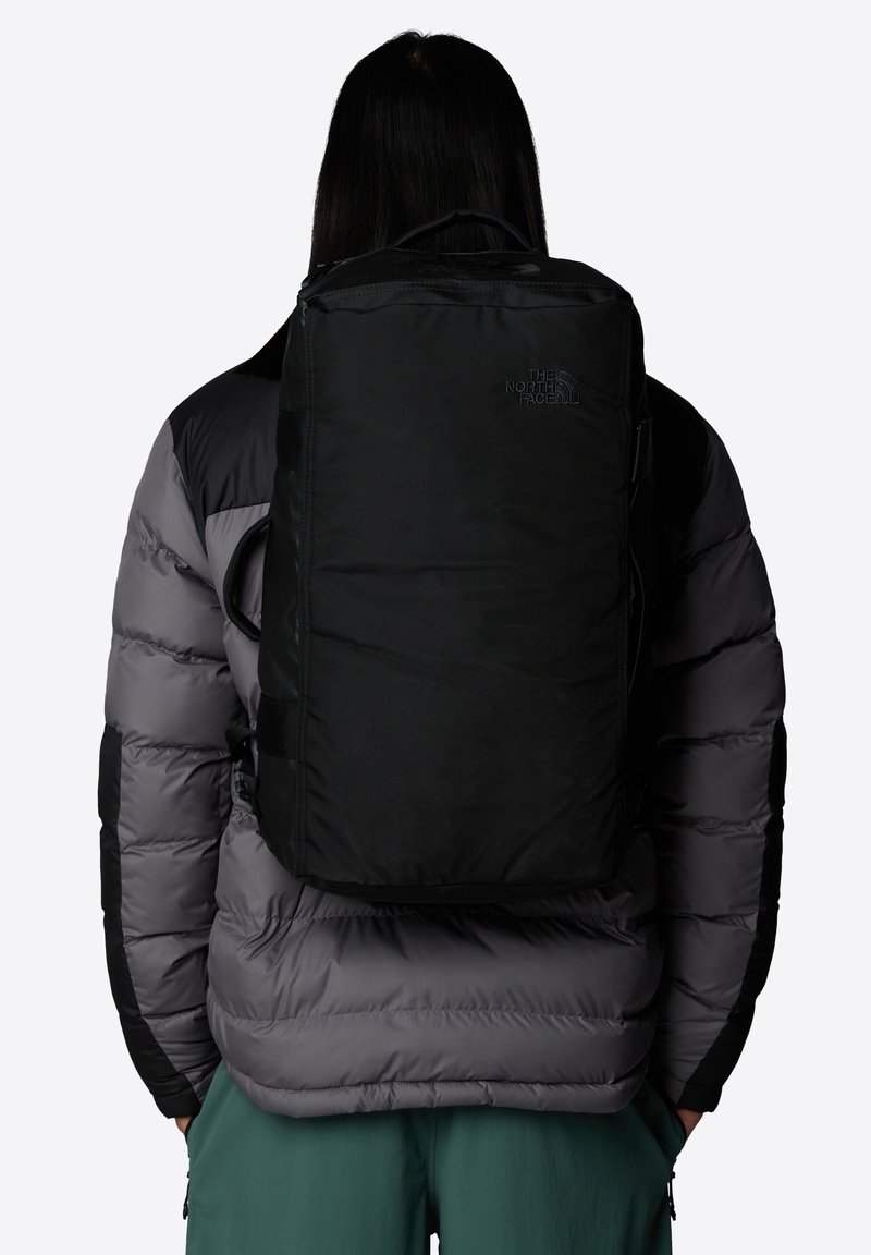 Svart ryggsäck tillverkad av hållbart tyg, med en rektangulär design, justerbara remmar och en logotypdetalj på framsidan.