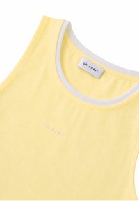 Haut jaune sans manches avec bordure blanche autour de l'encolure et une petite étiquette "OH APRIL" à l'intérieur du col.