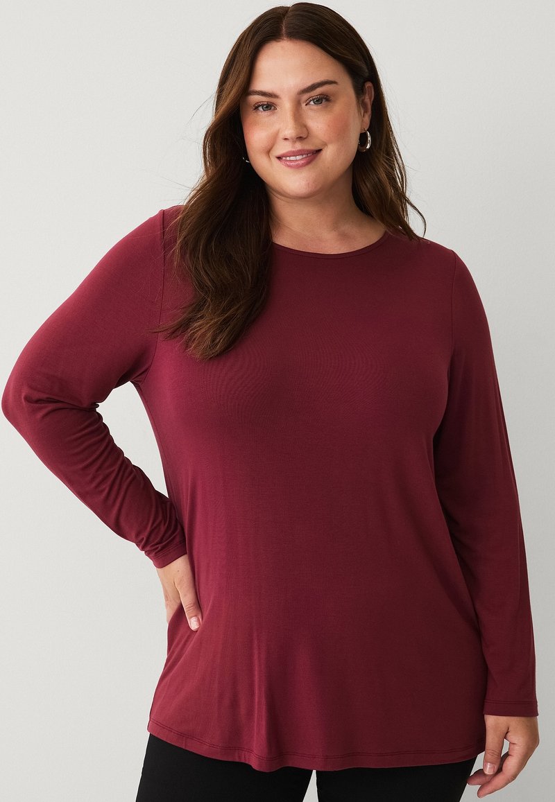 Long-sleeve maroon top made of smooth fabric with a round neckline. Features a relaxed fit and subtle stitching details along the hem.