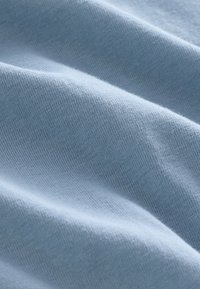 Světle modrá látka s měkkou, hladkou texturou, která má mírně žebrovaný vzor a jemné záhyby.