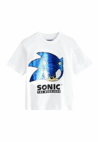 Bílý tričko s modrým flitrovým designem Sonic the Hedgehog na přední straně, s černým textem "SONIC THE HEDGEHOG" níže.