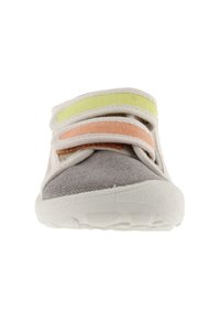 Zapatilla de lona gris con suela de goma blanca. Presenta dos correas de Velcro en rosa y amarillo. Textura suave, diseño minimalista.