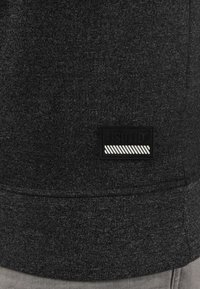 Svart melange sweatshirt med teksturert stoff, ribbede mansjetter og et rektangulært merke med hvite striper.