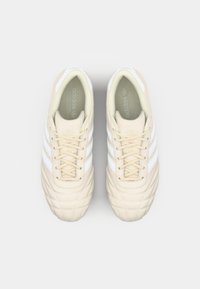 Bežiniai adidas sportbačiai su trimis baltomis juostelėmis, tekstūruotas raištelių dizainas, paminkštintas liežuvėlis ir siuvinėtas raštas ant pirštų dėklo.